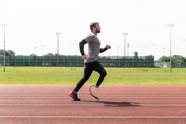 Sportowiec z protezą biegnący w pełnym ujęciu