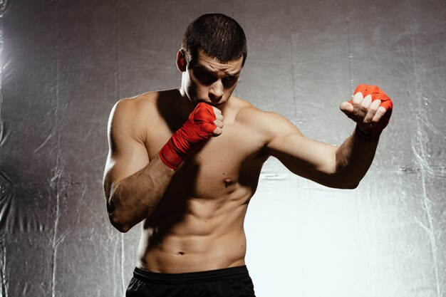 Sportowy bokser uderza z determinacją i ostrożnością nad srebrnym kground