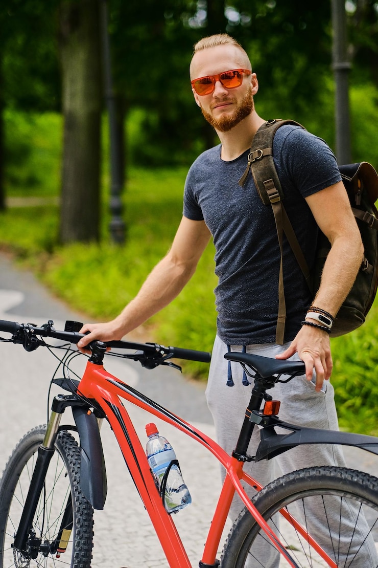 Bezpłatny plik Zdjęcie sportowy brodaty mężczyzna siedzi na czerwonym rowerze górskim na świeżym powietrzu.