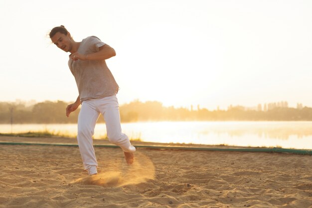 Sportowy capoeira wykonawca wykonuje ruchy na plaży