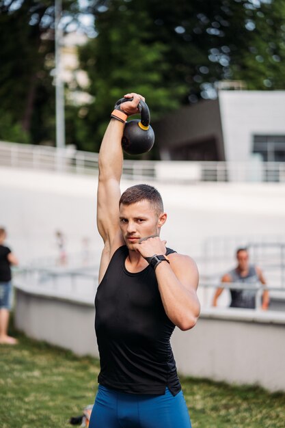 Sportowy facet trenujący z kettlebell. przystojny mężczyzna o dobrej budowie ciała. Siła i motywacja.