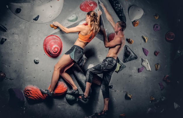 Sportowy mężczyzna i kobieta wspinaczka na ściance wspinaczkowej.