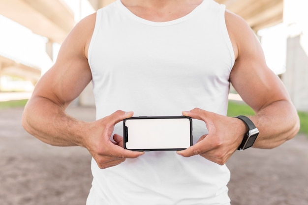 Sportowy mężczyzna trzyma jego telefon z pustym ekranem