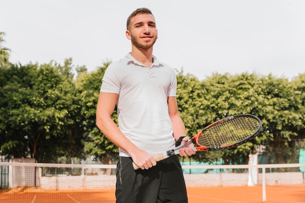 Bezpłatne zdjęcie sportowy młody gracz w tenisa pozować