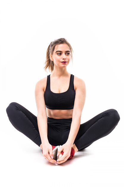 Sportwoman w czerń wierzchołku sportwear siedzi na podłoga odizolowywającej