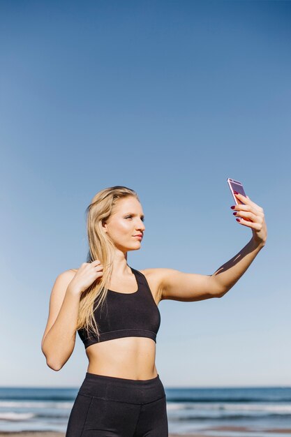 Sporty kobieta bierze selfie przy plażą