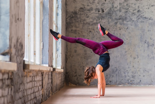 Bezpłatne zdjęcie sporty młoda kobieta robi zmniejszający się okładzinową drzewną pozę w loft