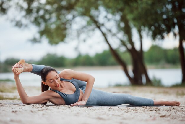 Sporty profesjonalne. Brunetka o ładnej sylwetce ma dzień fitness na plaży