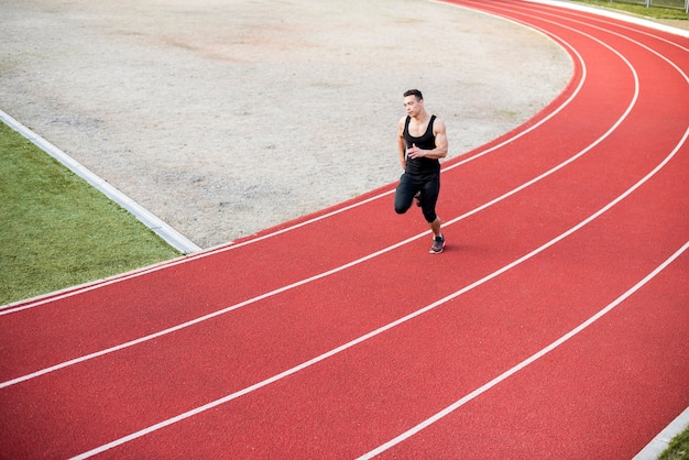 Sprawności fizycznej młoda męska atleta biega na biegowym śladzie