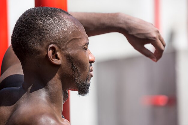 Sprawny sportowiec wykonujący ćwiczenia na stadionie. Afro lub Afroamerykanin mężczyzna na zewnątrz w mieście. Podciągnij ćwiczenia sportowe. fitness, zdrowie, koncepcja stylu życia