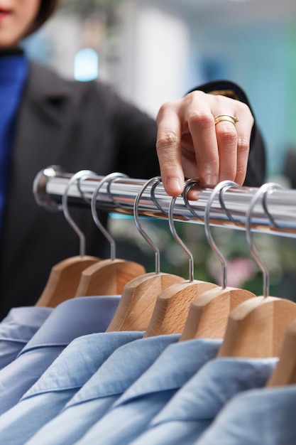 Bezpłatne zdjęcie sprzedawca butików w centrum handlowym ręcznie dopasowuje i bada odzież na zbliżeniu stojaka. ramię sprzedawcy zarządzające zapasami towarów i liczące ubrania w magazynie podczas pracy w sklepie