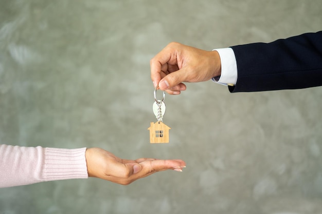 Sprzedawca w garniturze wysyłał klucze do domu nowemu właścicielowi. kupujący otrzymuje klucz od sprzedającego. koncepcja kupna i sprzedaży domu