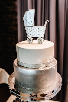 Srebrny tort urodzinowy lub chrzciny z bryczką dla chłopca. piękne dekoracje na baby shower party przy ścianie.