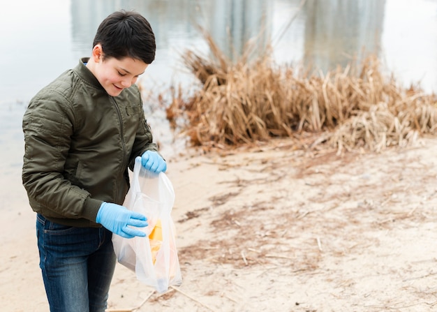 Średni strzał chłopca z plastikową torbą