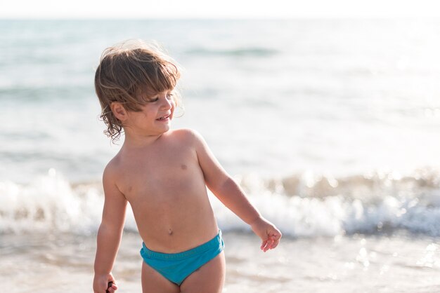 Średni strzał dzieciak patrzeje daleko od na plaży