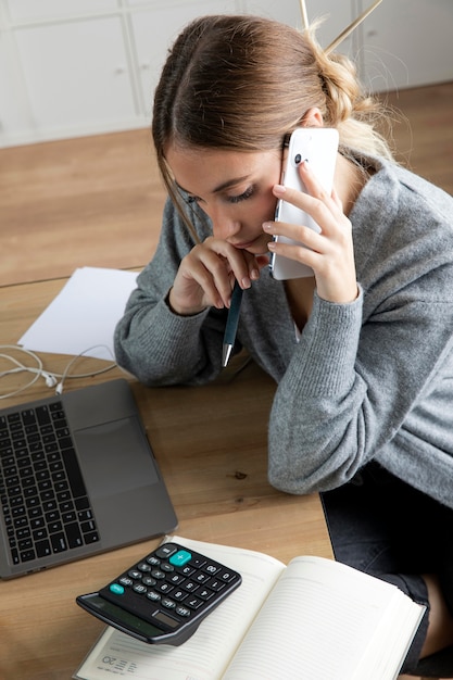 Bezpłatne zdjęcie Średni strzał freelancer siedzący na biurku