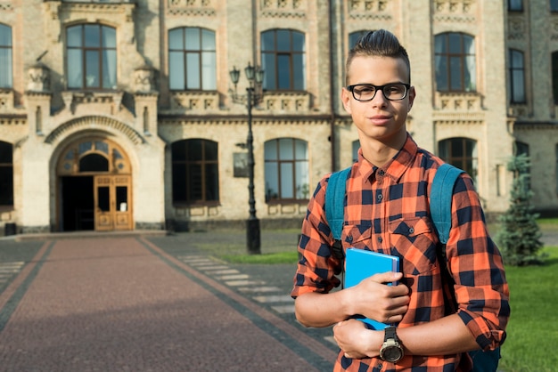 Bezpłatne zdjęcie Średni strzał highschool chłopiec trzyma książkę w rękach