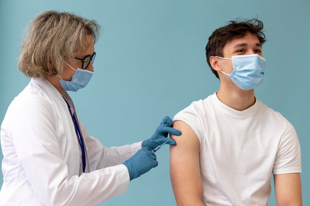 Bezpłatne zdjęcie Średni strzał mężczyzny otrzymującego szczepionkę