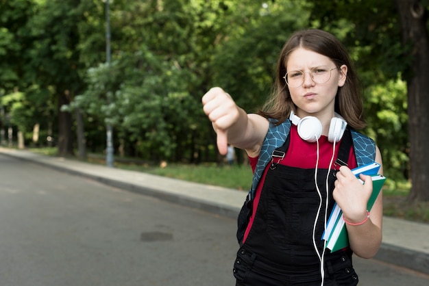 Bezpłatne zdjęcie Średni strzał rozczarowana highschool dziewczyna trzyma książki w ręce