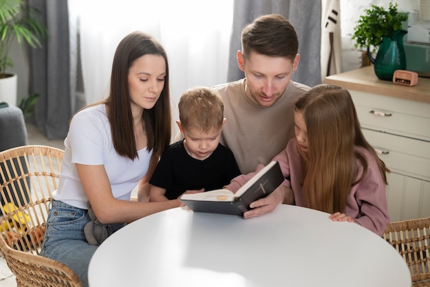 Średni strzał szczęśliwa rodzina czytająca biblię