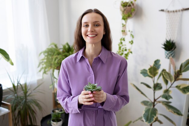 Średni strzał uśmiechniętej kobiety trzymającej roślinę