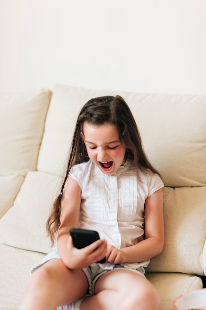 Średnia strzał smiley dziewczyna patrząc na telefon