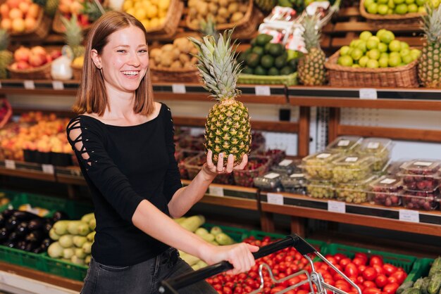 Średnia strzał smiley kobieta trzyma ananasa