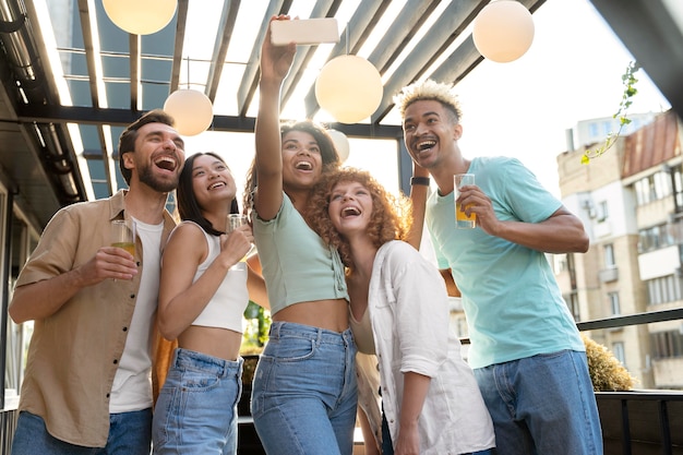 Bezpłatne zdjęcie Średnie ujęcie szczęśliwi przyjaciele robiący selfie