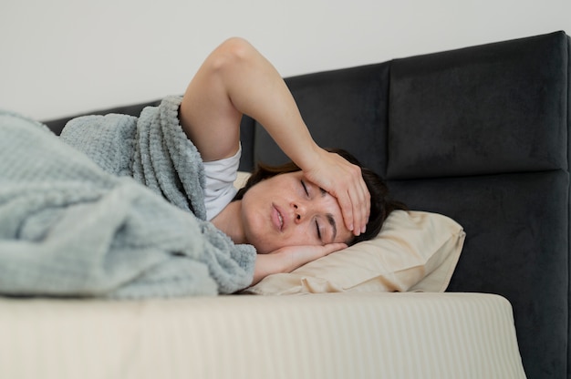 Średnio strzał chora kobieta leżąca w łóżku
