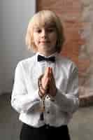 Bezpłatne zdjęcie Średnio strzał dzieciak modlący się z krucyfiksem