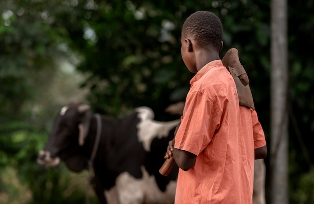 Bezpłatne zdjęcie Średnio strzał dzieciak patrzący na krowę