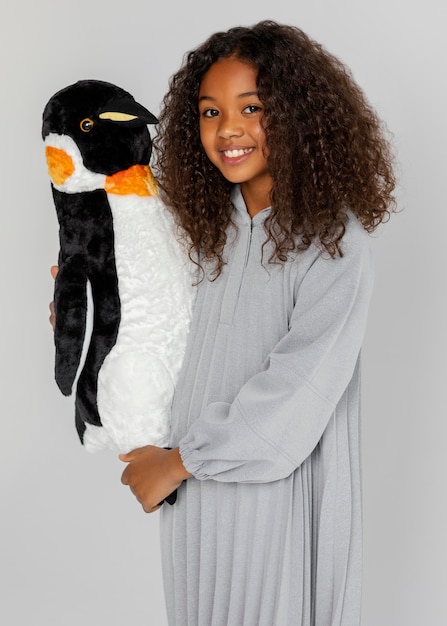 Bezpłatne zdjęcie Średnio strzał dziewczyna trzyma pingwina