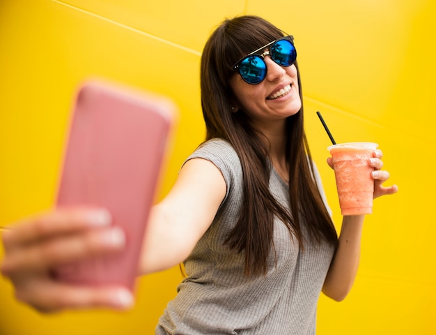 Średnio strzał dziewczyna z drinkiem przy selfie