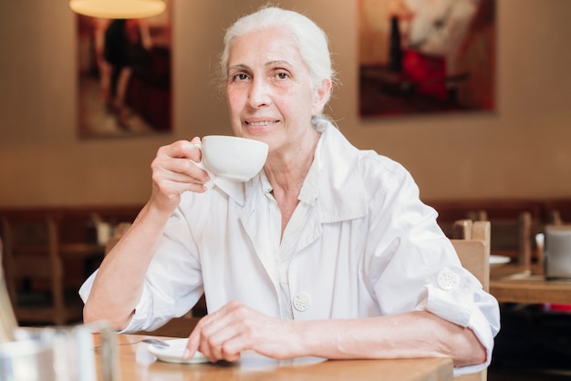 Bezpłatne zdjęcie Średnio strzał kobieta pije herbatę w restauracji