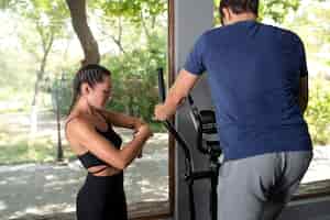 Bezpłatne zdjęcie Średnio strzał kobieta pomaga mężczyźnie ćwiczyć na siłowni