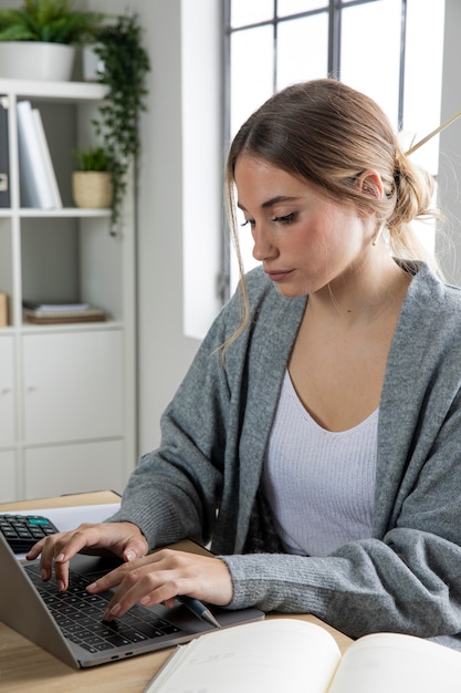 Bezpłatne zdjęcie Średnio strzał kobieta pracująca na laptopie