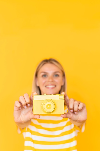 Bezpłatne zdjęcie Średnio strzał kobieta trzyma żółtą kamerę