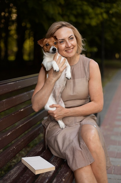 Średnio strzał kobieta trzymająca psa na zewnątrz