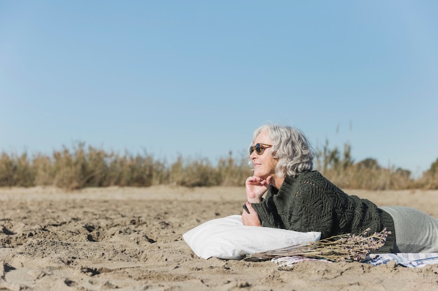 Bezpłatne zdjęcie Średnio strzał kobieta z okulary przeciwsłoneczne na plaży