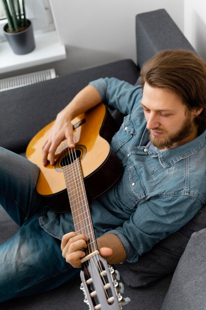 Średnio strzał mężczyzna gra na gitarze w domu