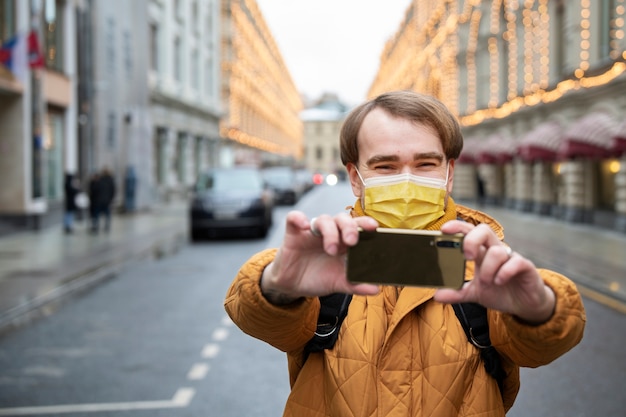 Bezpłatne zdjęcie Średnio strzał mężczyzna z maską robiący selfie