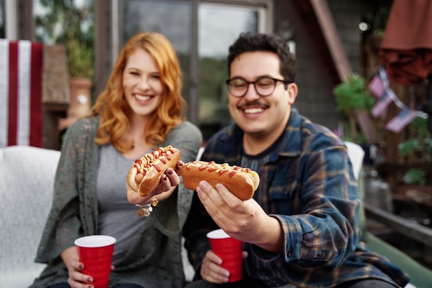 Bezpłatne zdjęcie Średnio strzał uśmiechnięci ludzie z napojami i hot-dogami