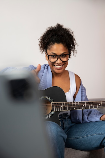 Bezpłatne zdjęcie Średnio strzał uśmiechnięta kobieta grająca na gitarze