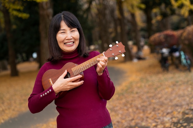 Bezpłatne zdjęcie Średnio strzał uśmiechnięta kobieta grająca na ukulele