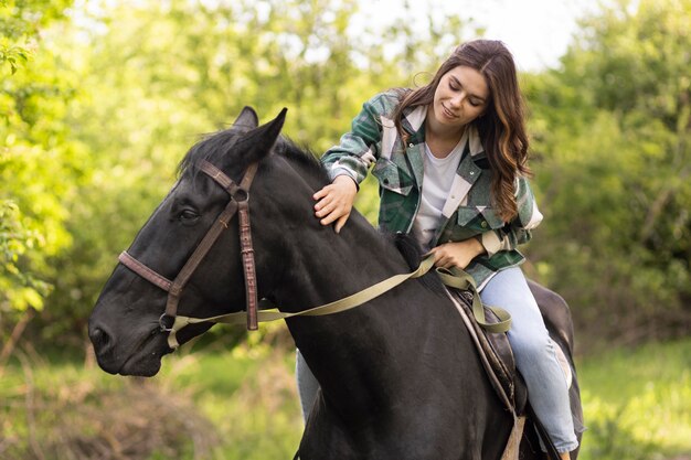 Średnio strzał uśmiechnięta kobieta jedzie na koniu