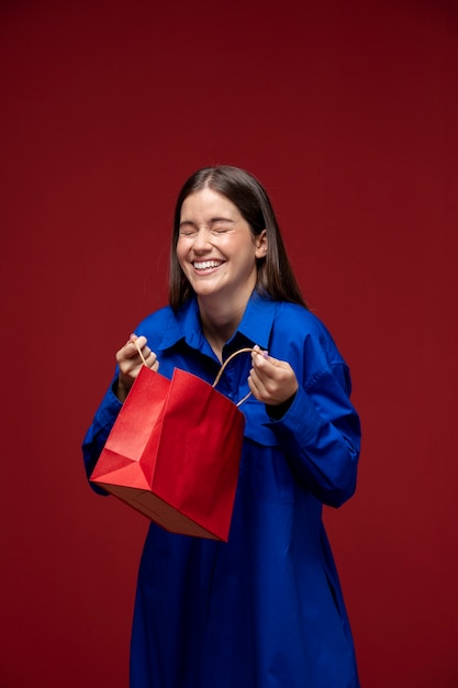 Bezpłatne zdjęcie Średnio strzał uśmiechnięta kobieta trzymająca papierową torbę