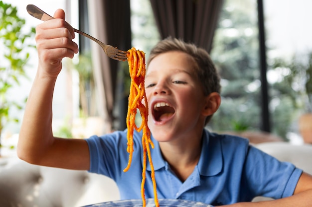 Bezpłatne zdjęcie Średnio strzał uśmiechnięty chłopiec ze spaghetti