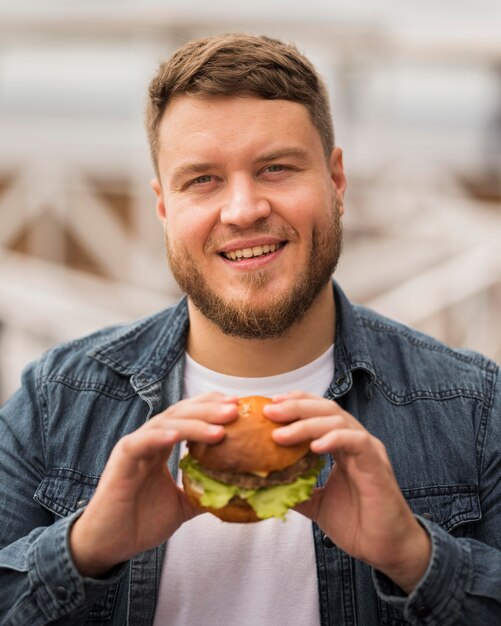 Średnio strzał uśmiechnięty mężczyzna trzyma burgera