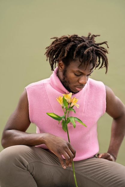 Bezpłatne zdjęcie Średnio strzał uśmiechnięty mężczyzna trzymający kwiat