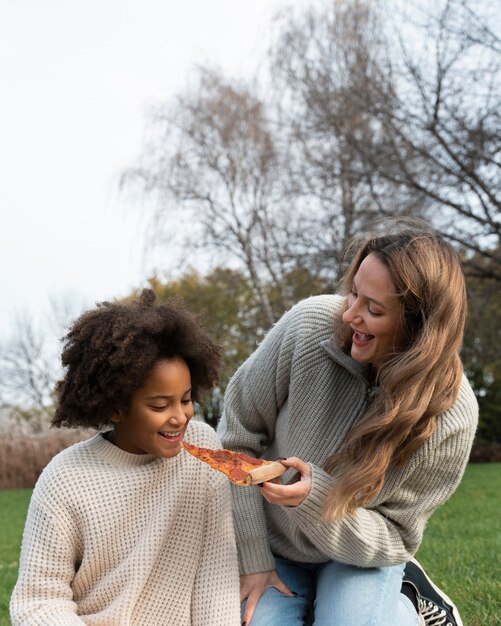 Średnio strzałowe uśmiechnięte kobiety z pizzą?